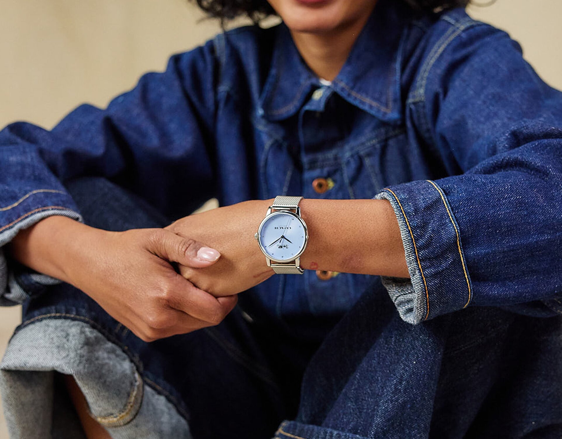 Model wearing coach grand stainless steel mesh bracelet watch with light blue dial