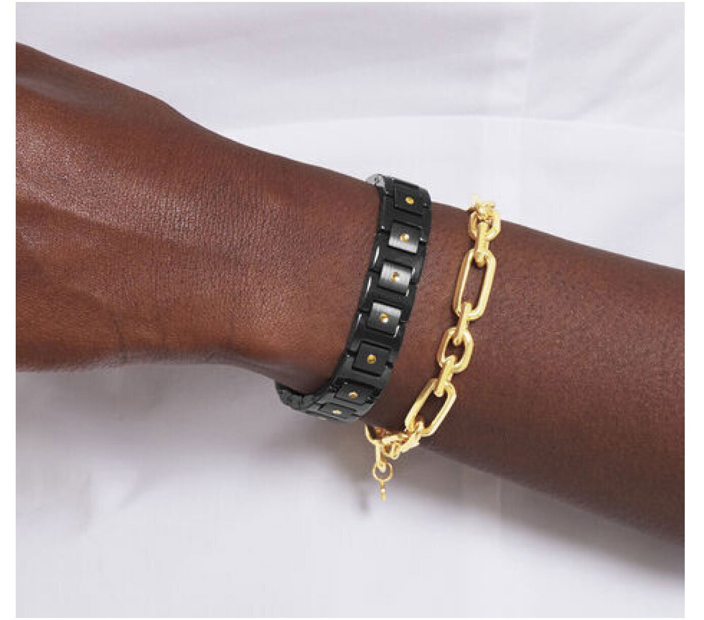 Model wearing a black Movado SE ceramic bracelet with yellow gold  PVD accents and a gold-plated sterling silver faceted chain bracelet