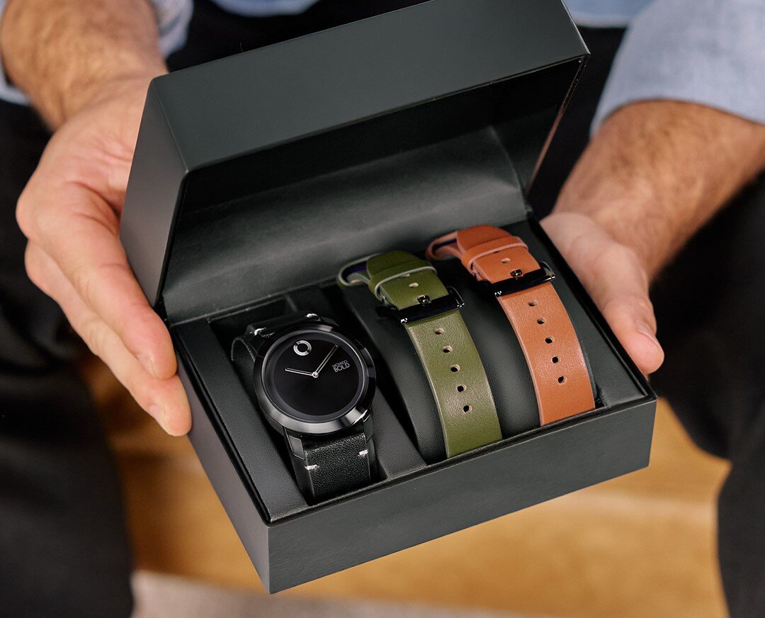 Model holding Movado trend gift set box with black strap and interchangable green and brown strap