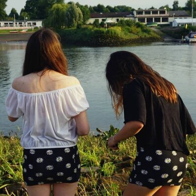 Two young women walking beside a river enjoying time outdoors, supporting healthy lifestyles with Level Health insurance Plan A.