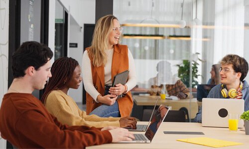 Colleagues chatting at their desks in an office.