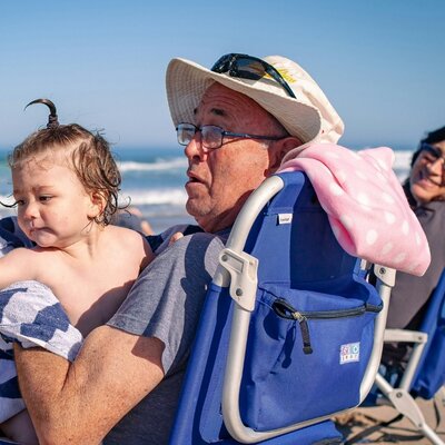 Grandparent carrying a child on the beach, capturing family wellbeing and peace of mind with Level Health insurance Plan D.
