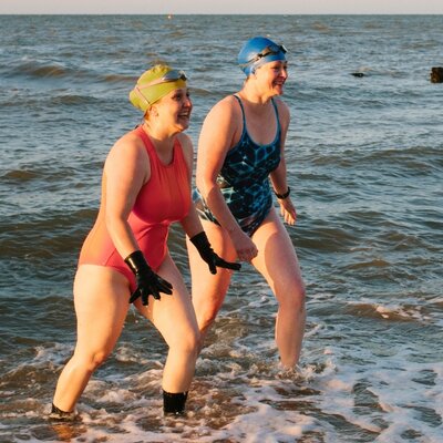 Two women taking part in a sea swim, promoting active lifestyles, wellness and Level Health health insurance Plan C.