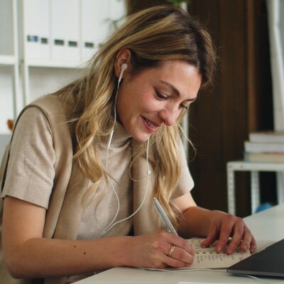 Young woman writing notes while working from home, representing everyday wellbeing and Level Health health insurance Plan Pro.