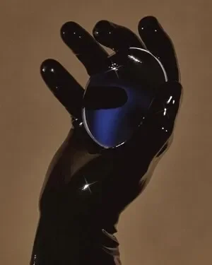 A hand that is holding something in it's palm and wearing a black latex glove