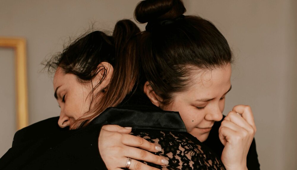two women hugging as they go through the tasks of mourning