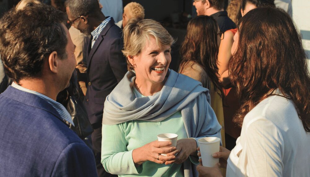 woman smiling and talking to group of people as part of a behavioral experiments worksheet exercise