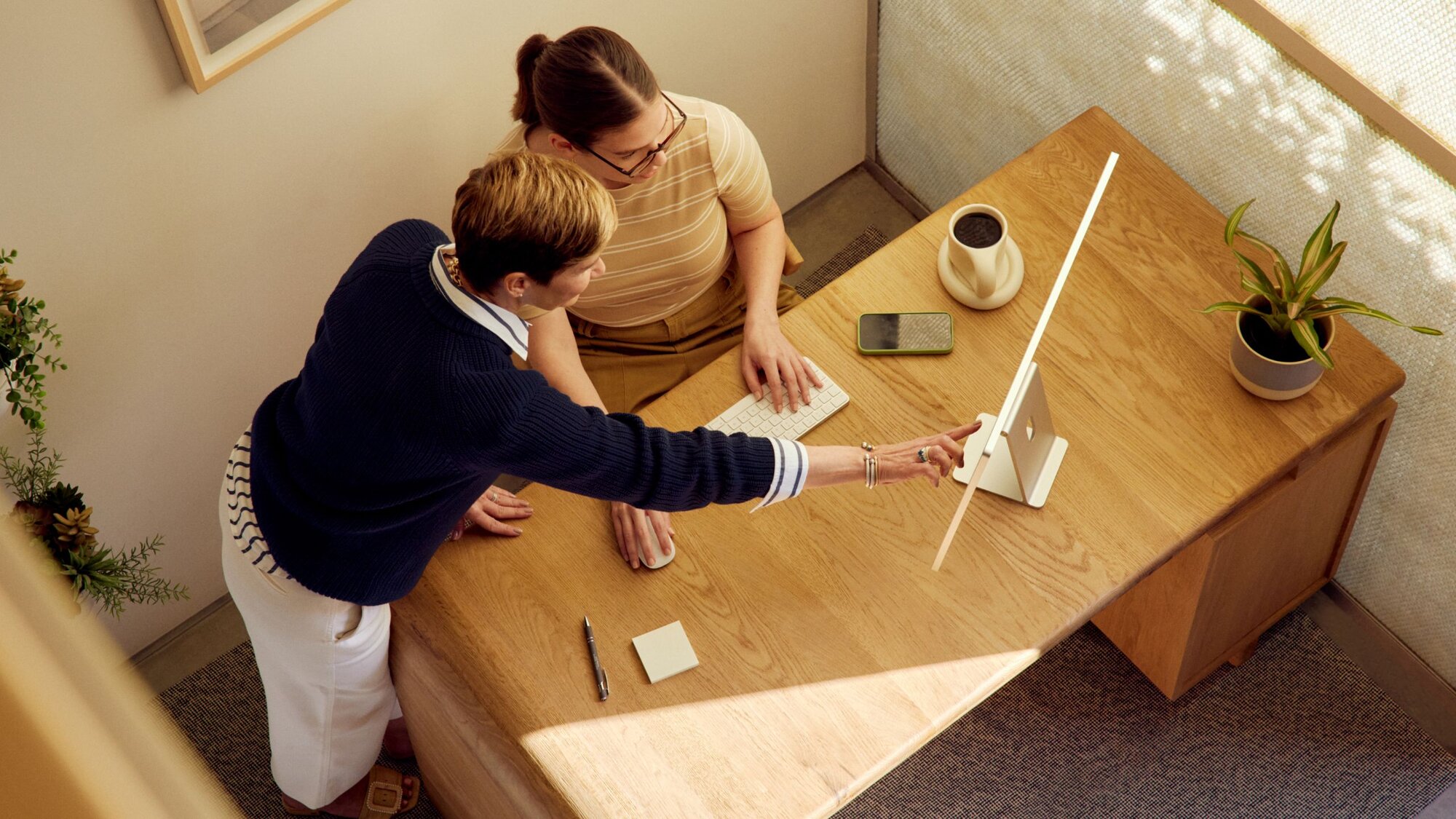 two practitioners at a desk looking at a desktop computer