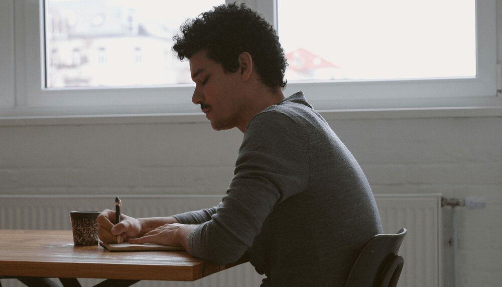 man sitting at desk and writing in an anger journal