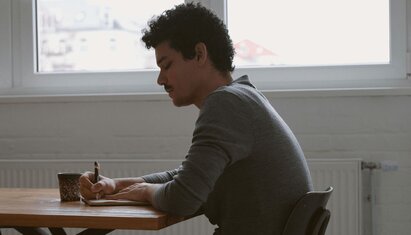 man sitting at desk and writing in an anger journal