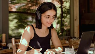 girl with glasses and headphones sitting at desk and studying with ADHD
