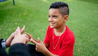 child doing sign language with an adult out of frame