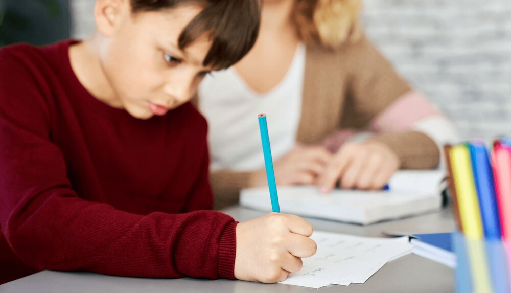 child writing at desk and using cbt triangle for kids worksheet