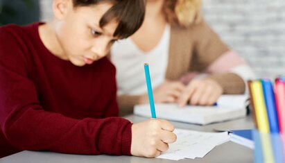 child writing at desk and using cbt triangle for kids worksheet