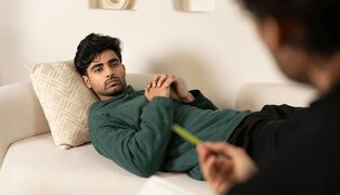 A male client reclines on the couch during an accelerated resolution therapy session