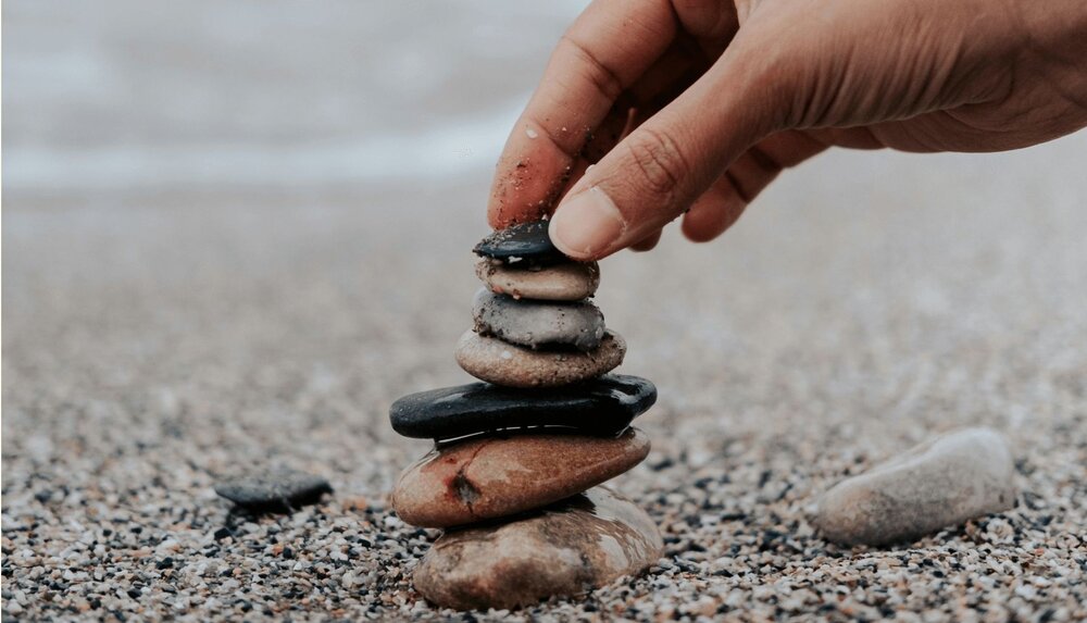 person stacking rocks on beach after using values discussion questions to identify core values