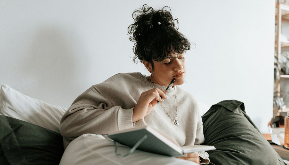 woman sitting down and thinking about what to write in her gratitude journal worksheet
