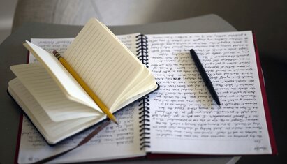 closeup image of notebooks with writing where a person uses positive journal prompts