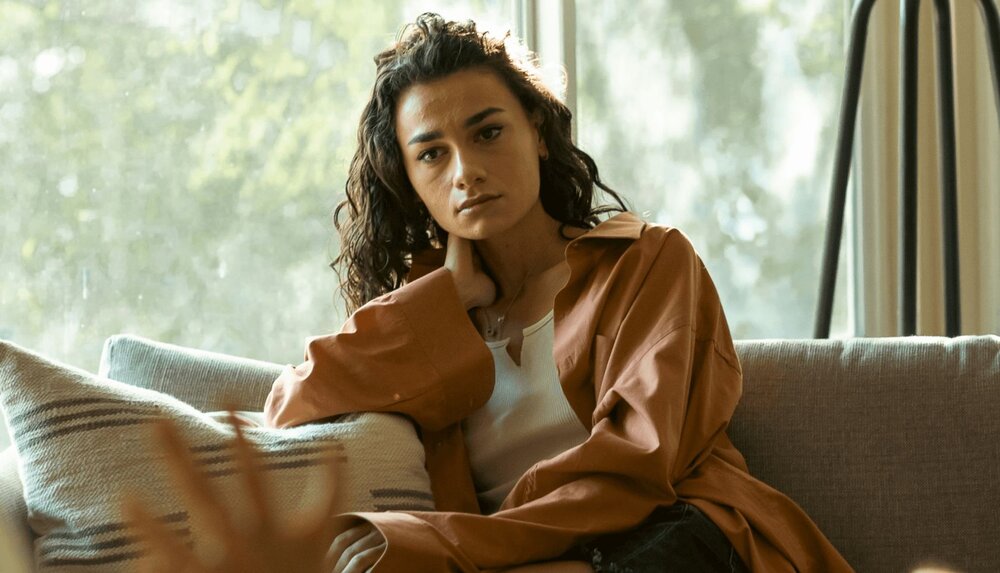 woman sitting and staring out into space using DBT mindfulness skills to regulate emotions