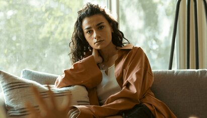 woman sitting and staring out into space using DBT mindfulness skills to regulate emotions