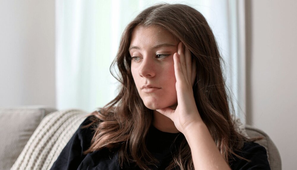 A therapist puts her hand on her face as she thinks about navigating client resistance in therapy