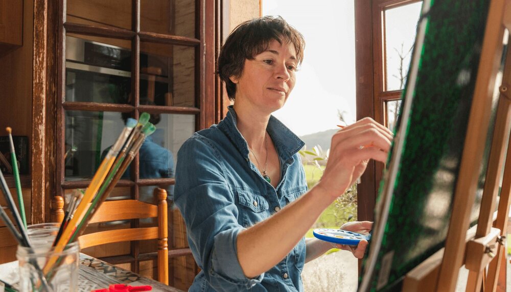 An artist works on a painting at her easel - for therapists, working with creative professionals is an extremely rewarding experience.