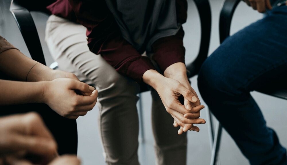 closeup of person's hands while a clinician takes SOAP notes in group therapy settings