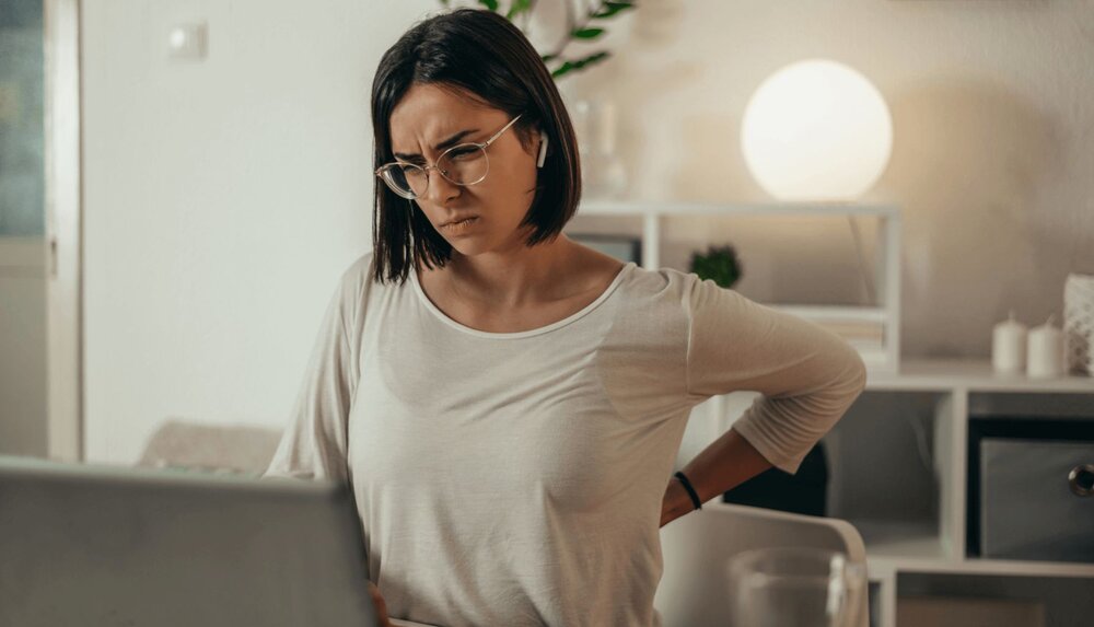 An image of a woman holding her lower back because she suffers from back pain that requires chronic pain management