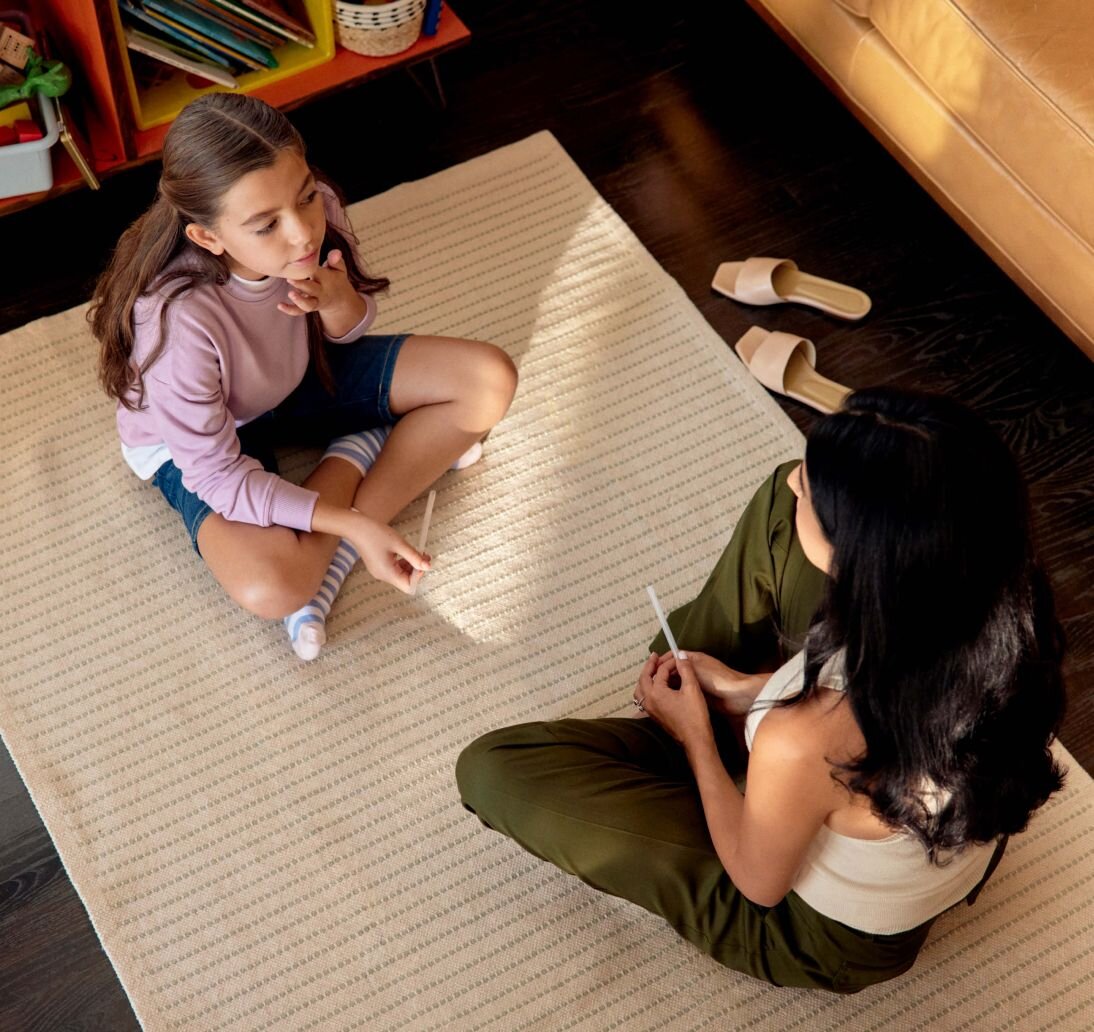 Speech-language pathologist working with child on rug