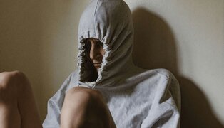 person sitting down and pulling their hood tight over their head avoiding a situation