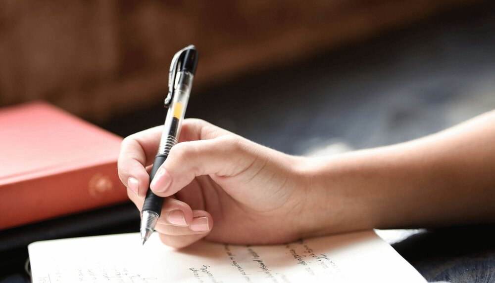 A therapist holds a pen and notebook to write PIRP notes after a session