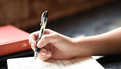 A therapist holds a pen and notebook to write PIRP notes after a session
