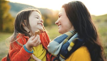 adult holding child and smiling as she helps her through a how I feel worksheet