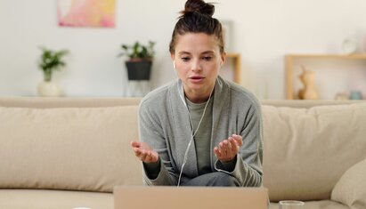 woman sitting in a couch on a telehealth call