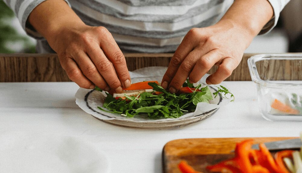 person making a plate of food and using healthy habits worksheet to establish habits