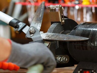 Hedge trimmer blade being sharpened on a grinder wheel