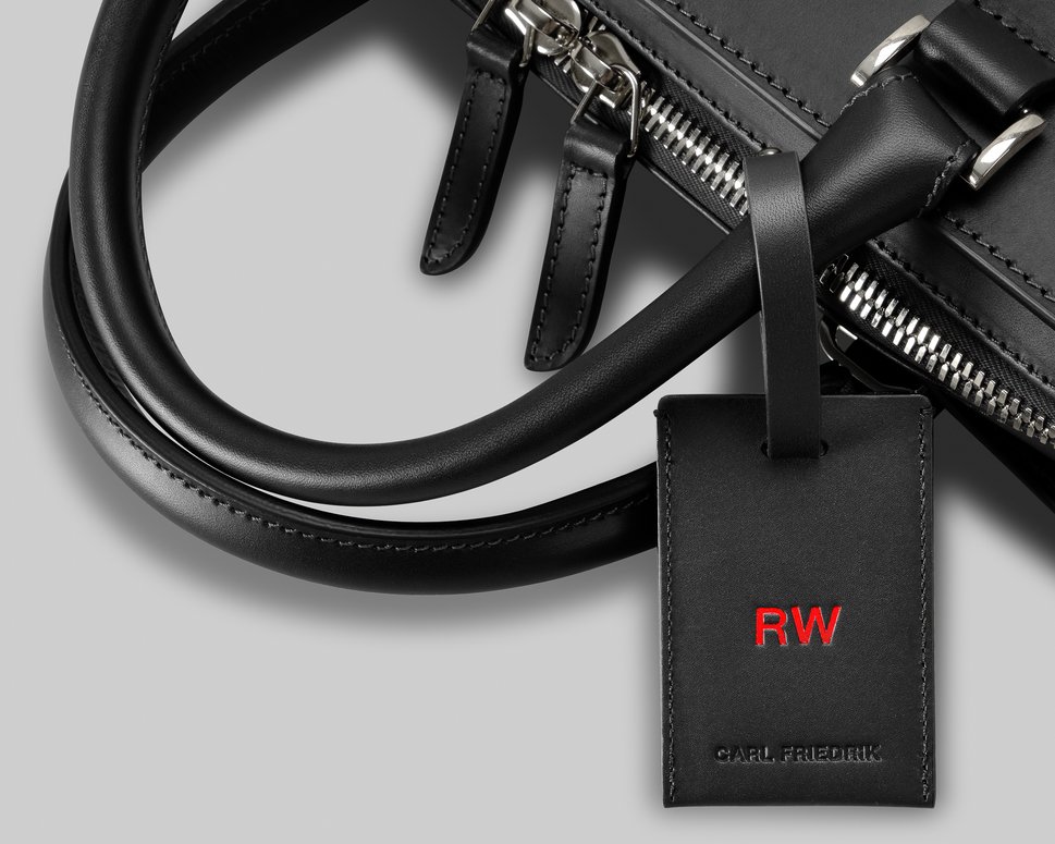 Customised black leather luggage tag attached to black Palissy briefcase