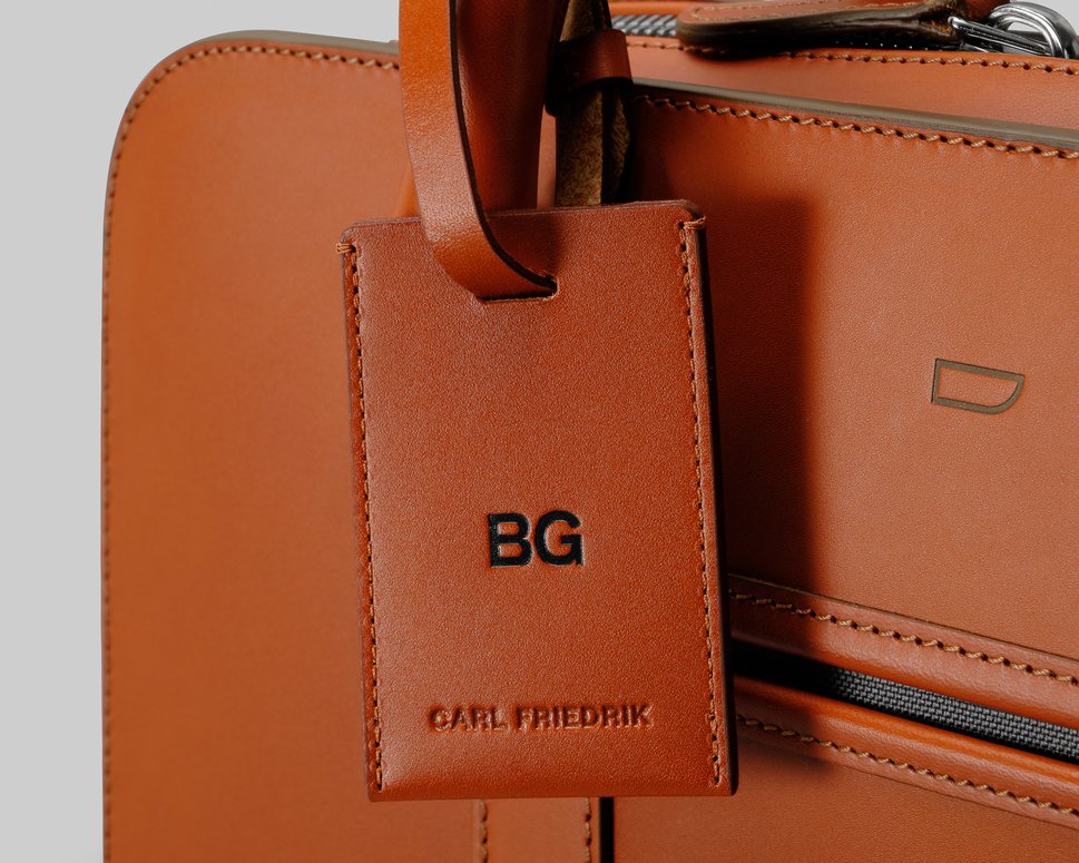 Brown leather luggage tag attached to brown Palissy briefcase