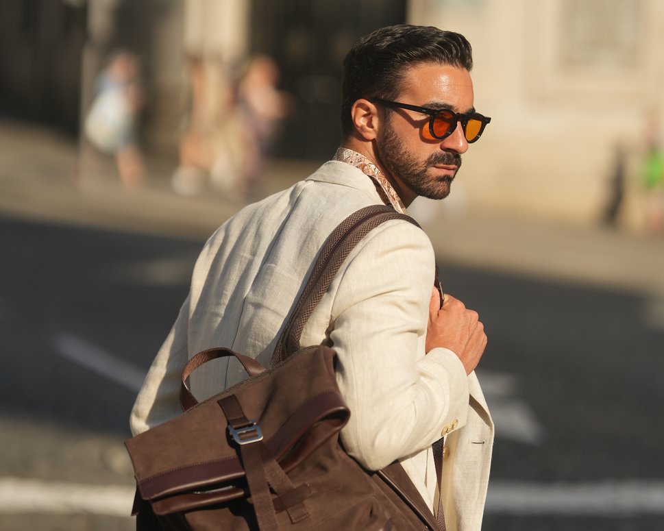 Man wearing brown nubuck backpack walks across street