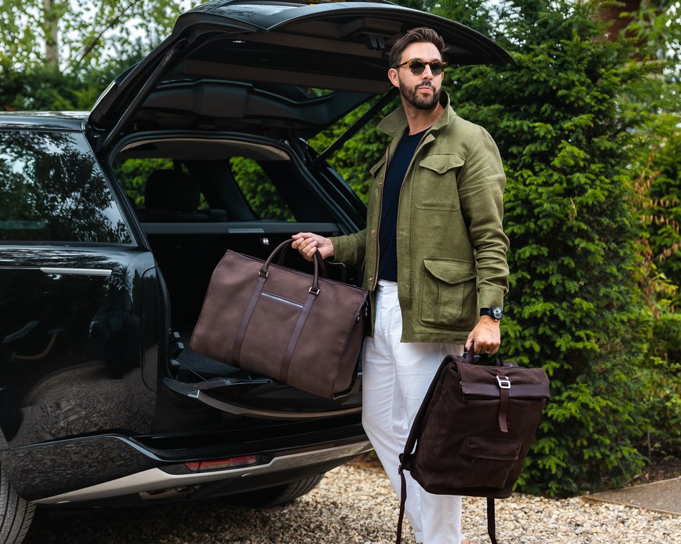 Man places brown nubuck backpack and weekend bag into car