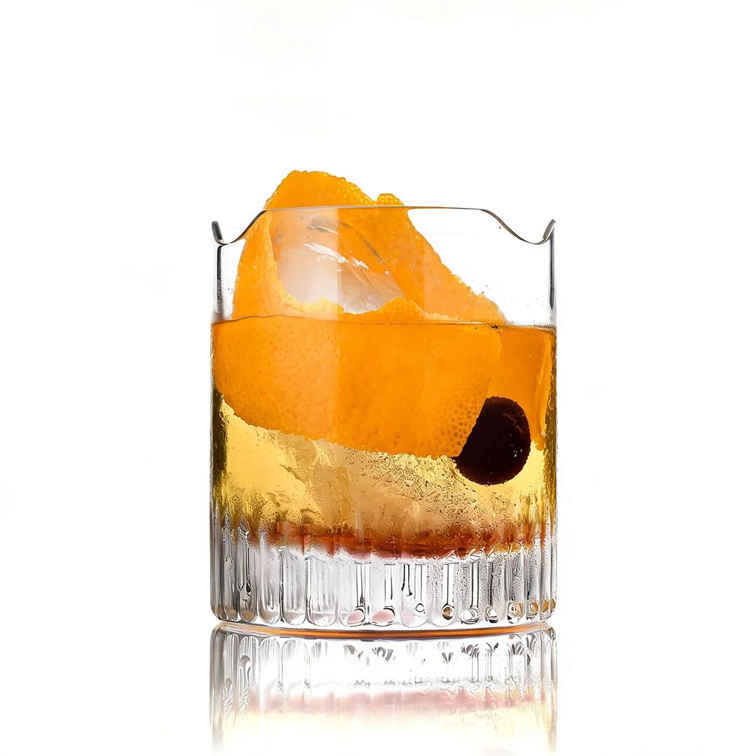 Whiskeyglas mit Orangenschale und Kirsche auf weißem Hintergrund.