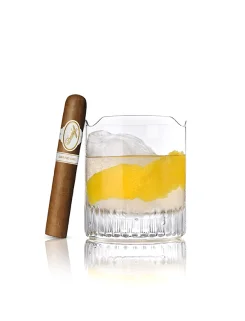 Davidoff Grand Cru-Zigarre neben einem Whiskeyglas mit Zitronenzeste und Eis auf reflektierender Oberfläche.