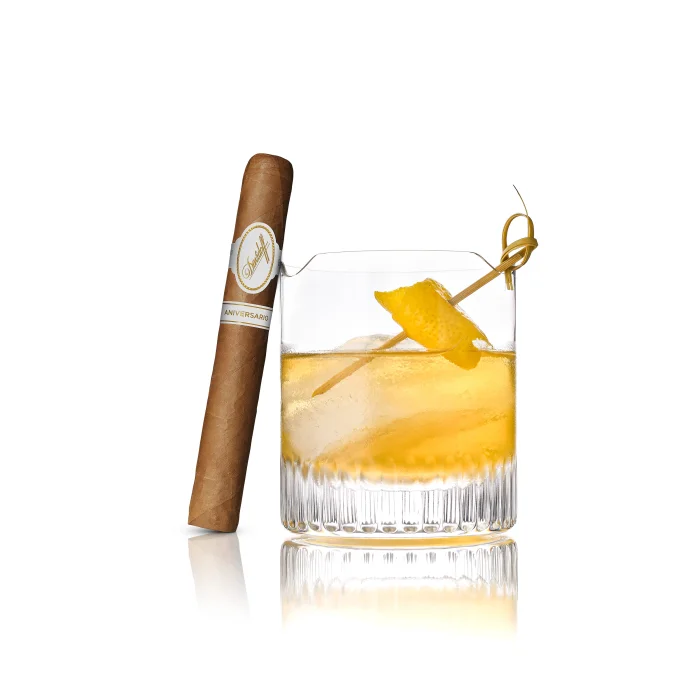Davidoff Aniversario No. 3 cigar beside a citrus cocktail with ice and lemon twist.