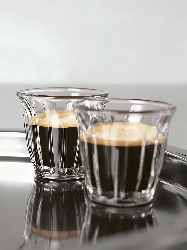 Zwei Espressoshots auf einem reflektierenden Tablett.