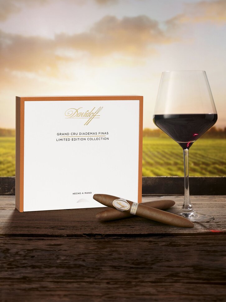 Davidoff Grand Cru Diademas Finas with cigars and wine, vineyard backdrop.