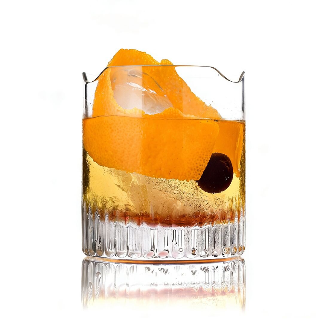 Whiskeyglas mit Orangenschale und Kirsche auf weißem Hintergrund.