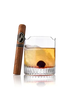 Eine Davidoff-Zigarre neben einem Whiskeyglas mit Eis und Kirsche, strahlt elegante Luxus aus.