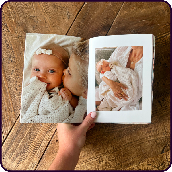 Hand holding open a baby memory book with newborn photo