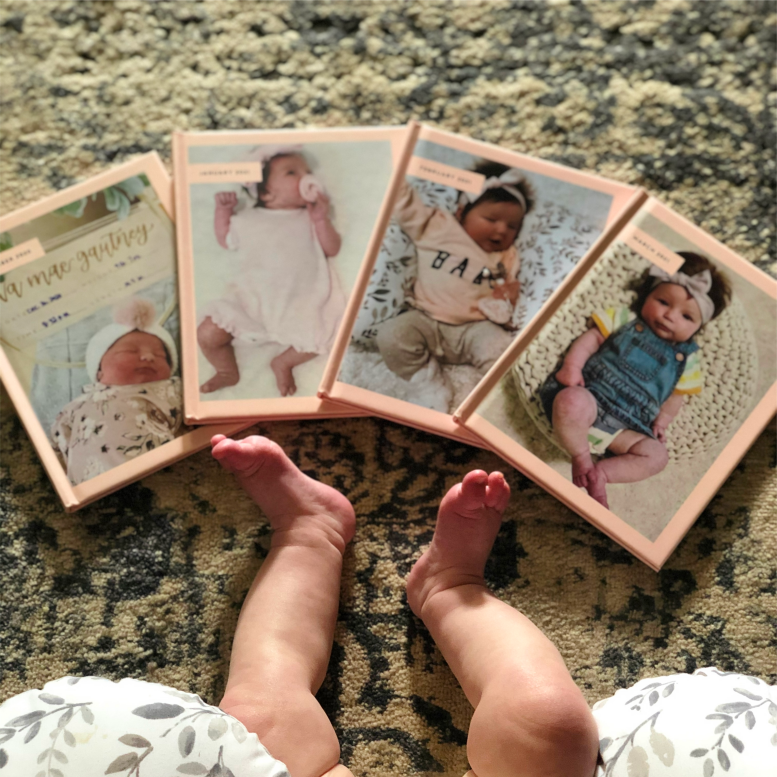 Baby looking at collection of custom baby photo albums in blush pink color