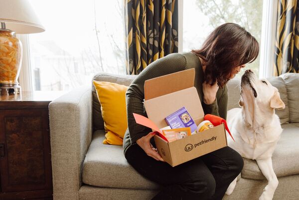 Women holding a PetFriendly box, kissing her dog